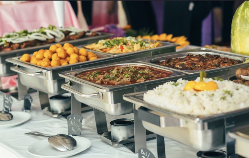 Bawarchi's catering setup with chafing dishes of curries, rice and appetizers